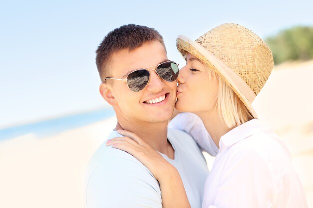 mujer besando a un hombre en la playa