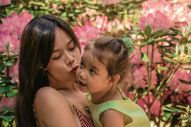 Foto mujer besando a su hija mientras está de pie junto a las plantas