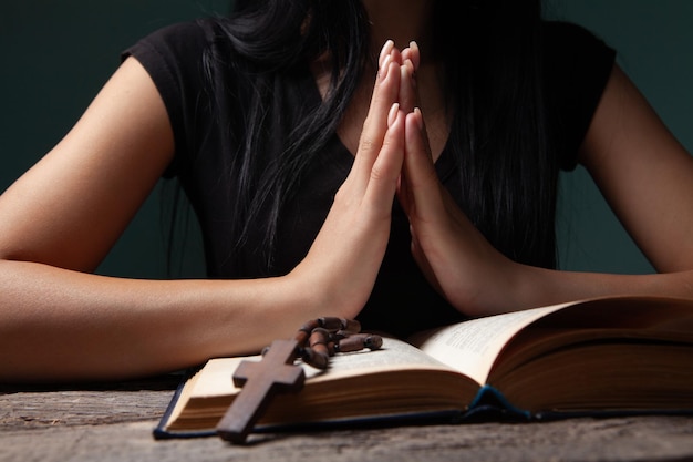 Foto mujer con biblia santa y cruz sobre fondo negro