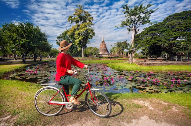 Mujer con bicicleta cerca del templo en Tailandia