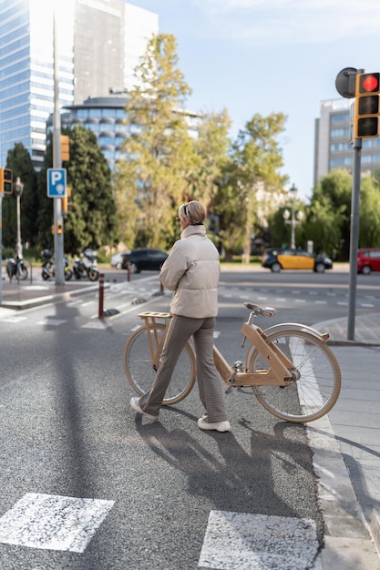 Foto mujer con bicicleta cruzando la carretera asfaltada