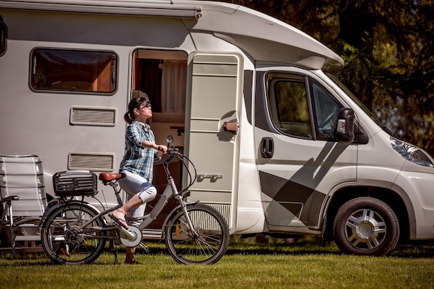 Mujer en bicicleta eléctrica descansando en el camping. Viajes de vacaciones familiares, viajes de vacaciones en autocaravana, VR Caravan car Vacation.