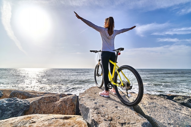 Mujer con una bicicleta en una orilla