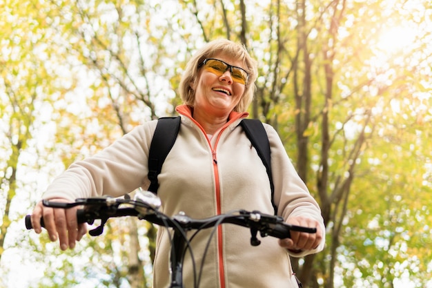 Una mujer en bicicleta paseos por la carretera en el parque de la ciudad.