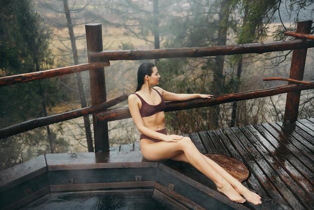 Mujer en bikini bañándose en un baño de estilo japonés al aire libre