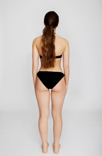Foto mujer en bikini de pie contra un fondo blanco