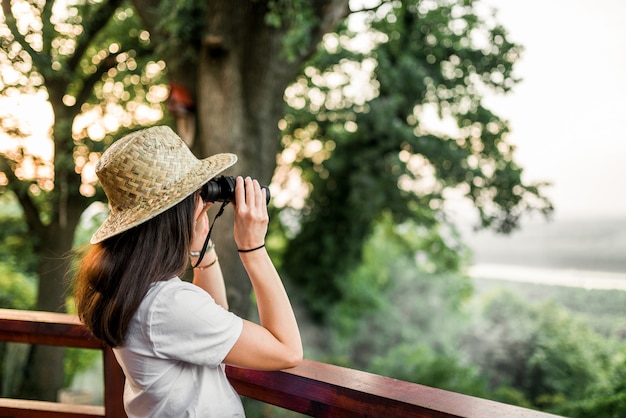 Mujer con binoculares mirando el bosque.