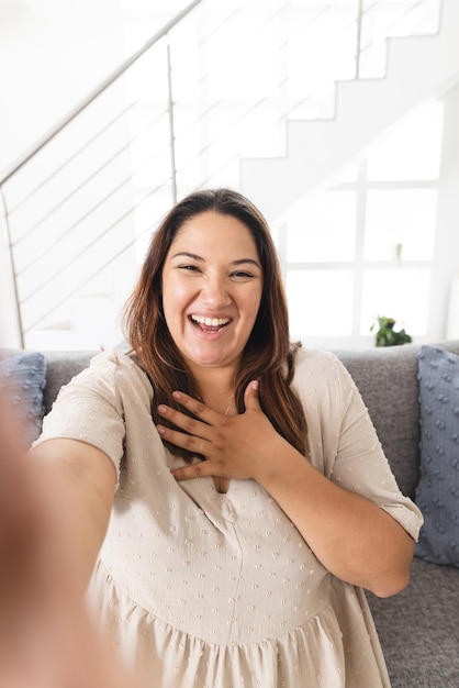 Foto mujer biracial joven y alegre tomando una selfie en casa con espacio para copiar