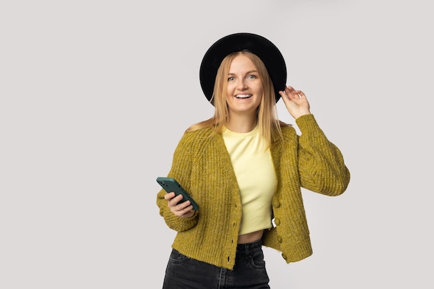 Mujer blanca emocionada riéndose mientras usa un teléfono celular aislado sobre fondo gris foto de alta calidad