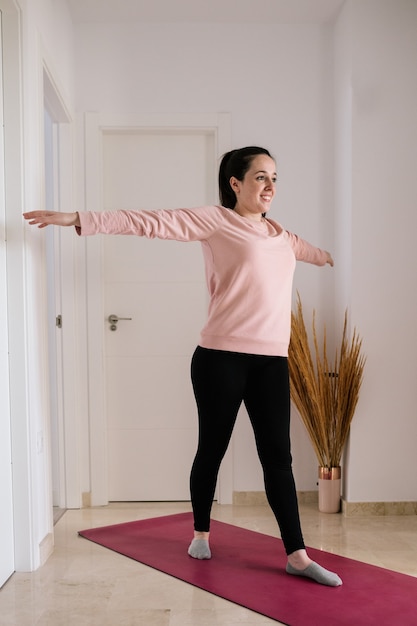 Mujer blanca de pelo negro haciendo yoga en casa