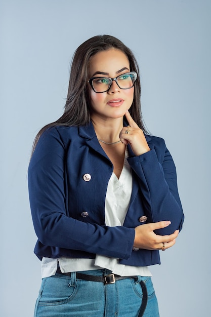 Una mujer con un blazer azul se para frente a un fondo azul.