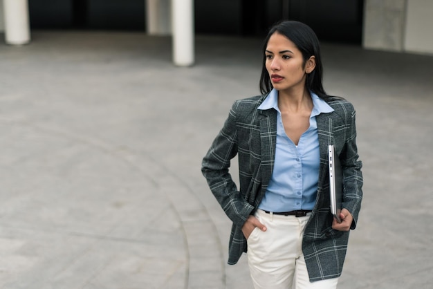 Una mujer con un blazer a cuadros camina por la calle.