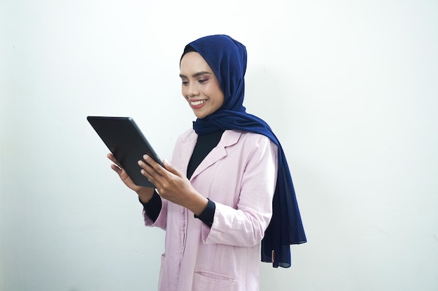 Una mujer con un blazer rosa sostiene una tableta.