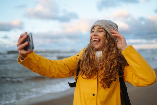 Mujer bloguera de viajes se toma selfie para redes sociales junto al mar atardecer Viajes turismo concepto de relax