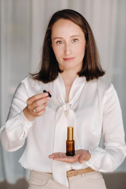 Una mujer con una blusa blanca sosteniendo una botella de aromaterapia de aceite esencial