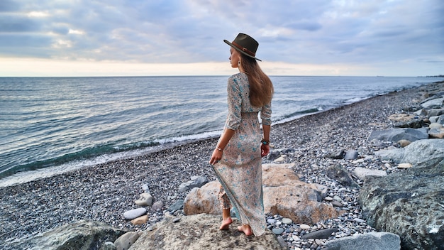 Mujer boho en vestido largo y sombrero de fieltro