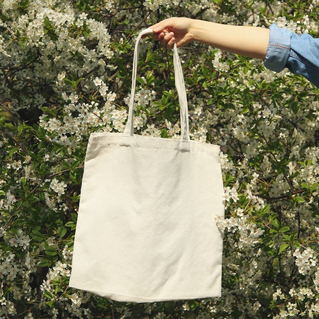 Mujer con bolsa de tela de lona en blanco. Primavera florece