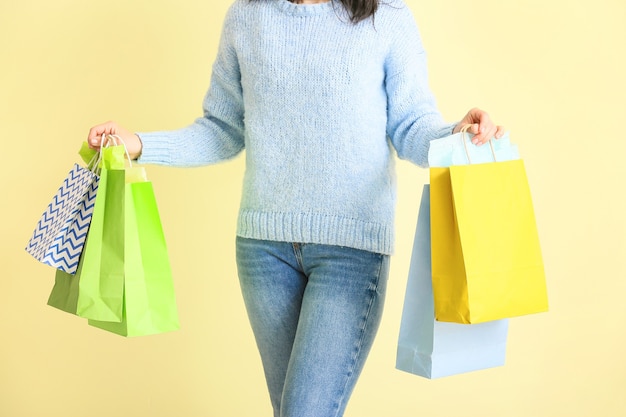 Mujer con bolsas de compras cerca de la pared de color