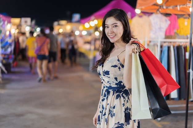 Mujer con bolsas en el mercado nocturno al aire libre