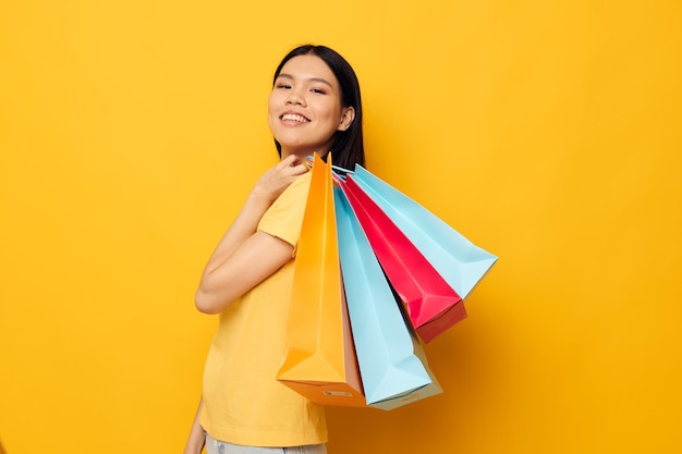 Mujer con bolsas en sus manos posando sobre fondo amarillo