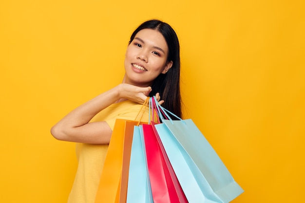 Mujer con bolsas en sus manos posando sobre fondo amarillo