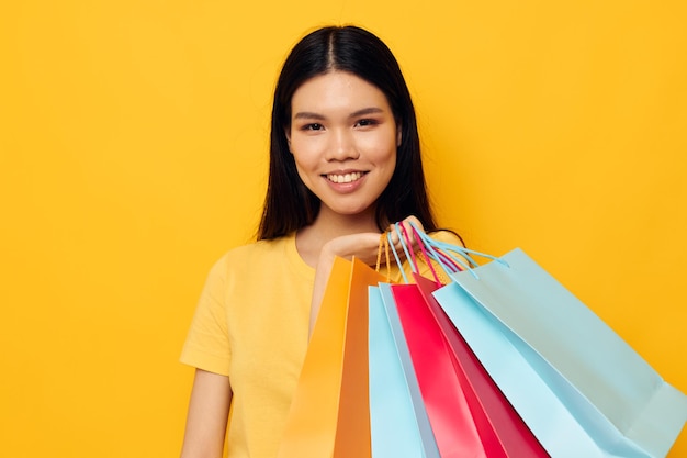 Mujer con bolsas en sus manos posando sobre fondo amarillo