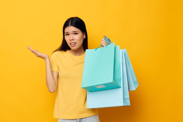 Mujer con bolsas en sus manos posando sobre fondo amarillo