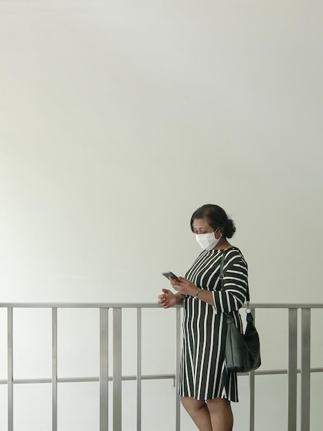 Mujer con bolso y mascarilla leyendo su celular