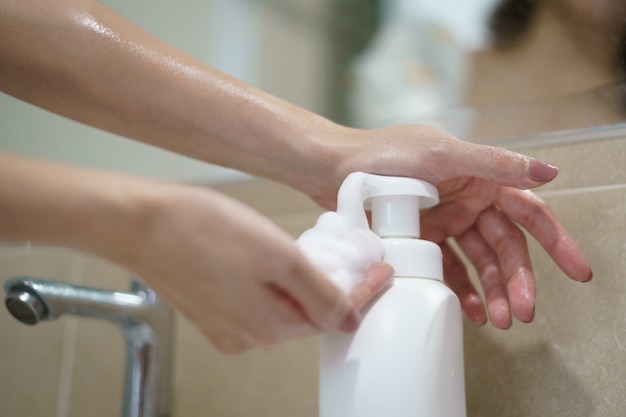 Mujer bombea jabón líquido en la palma para lavarse las manos