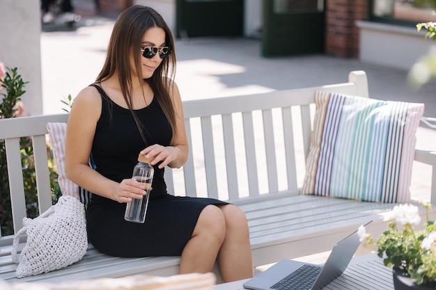 Una mujer bonita abre una botella de agua para beber un caluroso día de verano