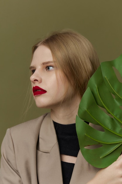 Mujer bonita con abrigo labios rojos moda hoja de palma fondo verde foto de alta calidad