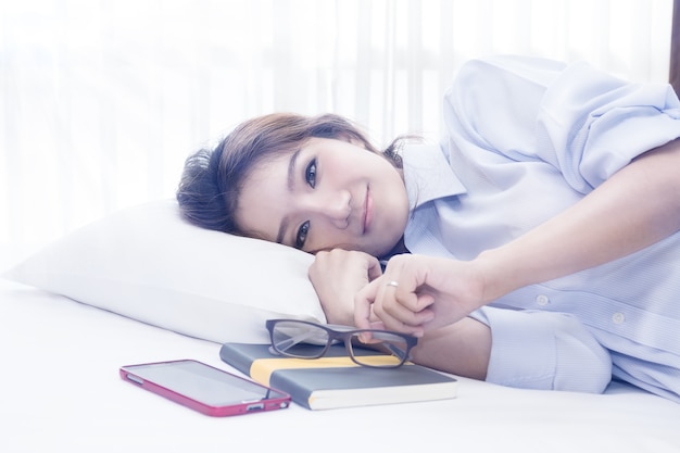 mujer bonita acostada en la cama después de despertarse y relajarse en la cama en casa