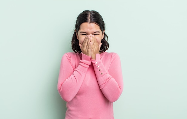 Mujer bonita adolescente que parece feliz, alegre, afortunada y sorprendida cubriendo la boca con ambas manos