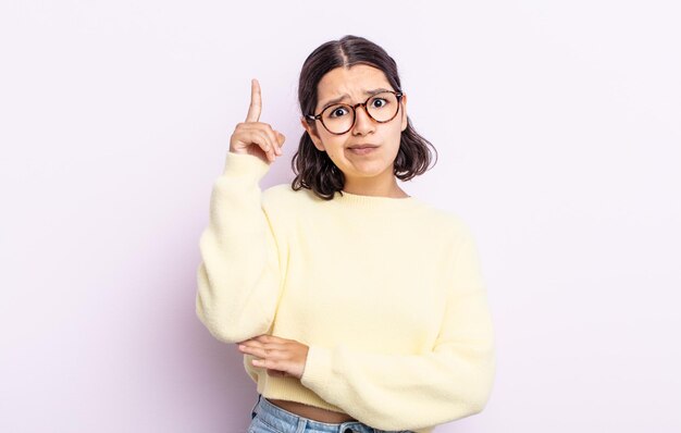 Mujer bonita adolescente que se siente como un genio sosteniendo el dedo con orgullo en el aire después de darse cuenta de una gran idea, diciendo eureka