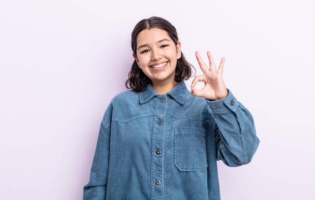 Mujer bonita adolescente que se siente feliz, relajada y satisfecha, mostrando aprobación con gesto bien, sonriendo