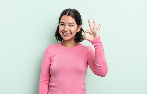 Mujer bonita adolescente que se siente feliz, relajada y satisfecha, mostrando aprobación con un gesto bien, sonriendo