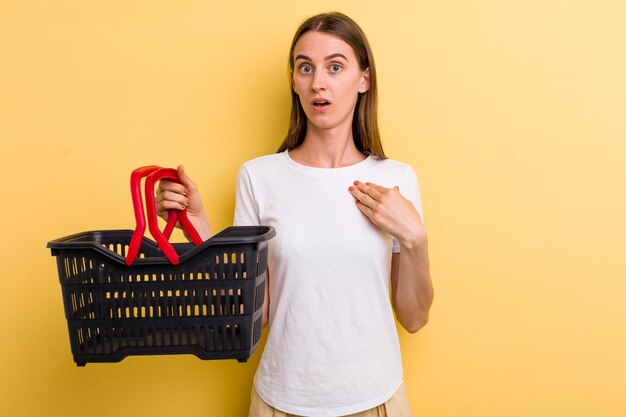 Mujer bonita adulta joven que sostiene una cesta de compras vacía