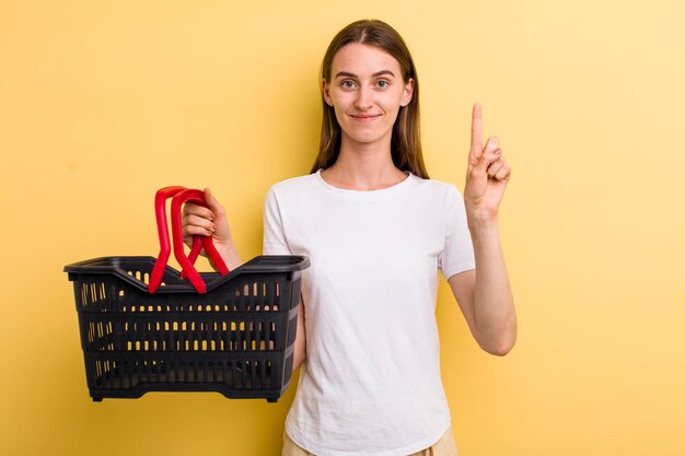 Mujer bonita adulta joven que sostiene una cesta de compras vacía