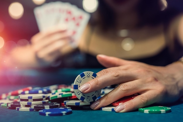 Mujer bonita afortunada jugando al póquer en la mesa de casino verde