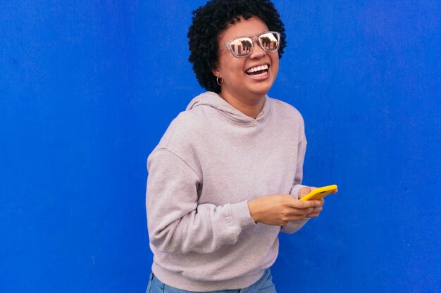 Mujer bonita afro enviando mensajes de texto y riendo