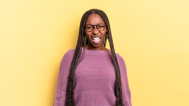 Mujer bonita afro negra que se siente disgustada e irritada, sacando la lengua, disgustando algo desagradable y asqueroso