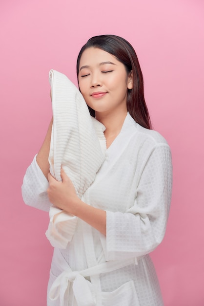 Mujer bonita alegre con piel sana secándose la cara con una toalla de algodón suave blanca después de la higiene matutina frente a la cámara