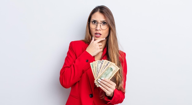 Mujer bonita asiática con la boca y los ojos bien abiertos y la mano en la barbilla concepto de negocios y billetes