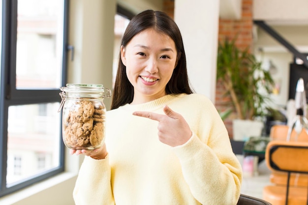 Mujer bonita asiática comiendo galletas en la sala de estar fresca