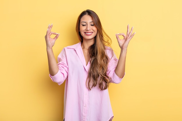 Mujer bonita asiática que parece concentrada y meditando, sintiéndose satisfecha y relajada, pensando o haciendo una elección