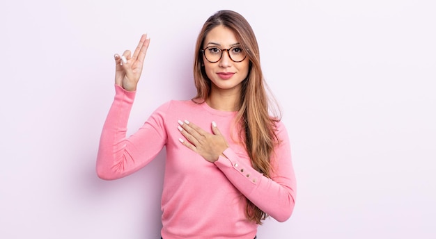 Mujer bonita asiática que parece feliz, segura y digna de confianza, sonriendo y mostrando el signo de la victoria, con una actitud positiva