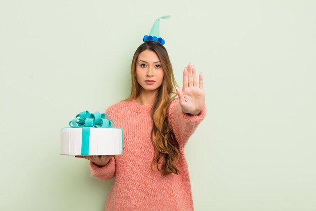 Mujer bonita asiática que parece seria mostrando la palma abierta haciendo un gesto de parada. concepto de cumpleaños