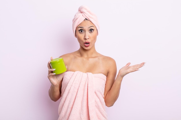 Mujer bonita asiática que parece sorprendida y conmocionada, con la mandíbula caída sosteniendo un objeto. mascarilla para el cabello y concepto de cuidado