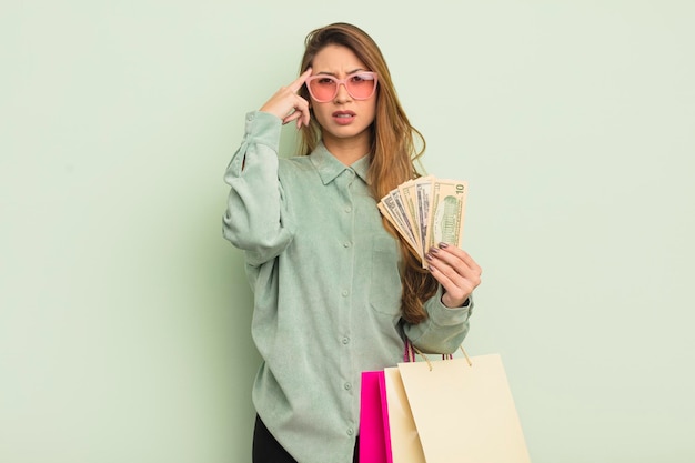 Mujer bonita asiática que se siente confundida y perpleja mostrando que estás loco por el concepto de bolsas de compras