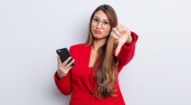 Foto mujer bonita asiática que se siente cruzada, mostrando los pulgares hacia abajo. concepto de negocio y teléfono.